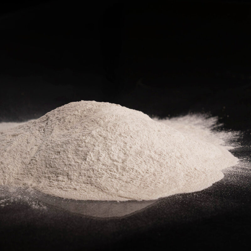 Side view of small mound of sand colored powder upon a shiny black background.