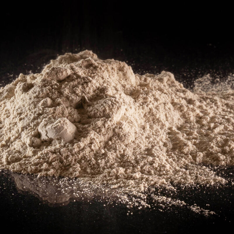 Tan powder in a lumpy pile on a black background.