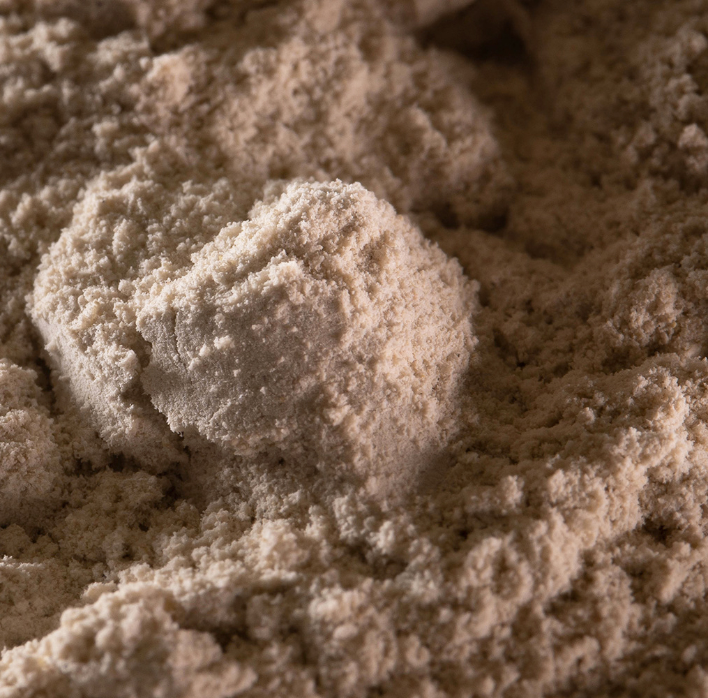 Close up shot of light brown powder with a few clumps of different sizes featured in the foreground.